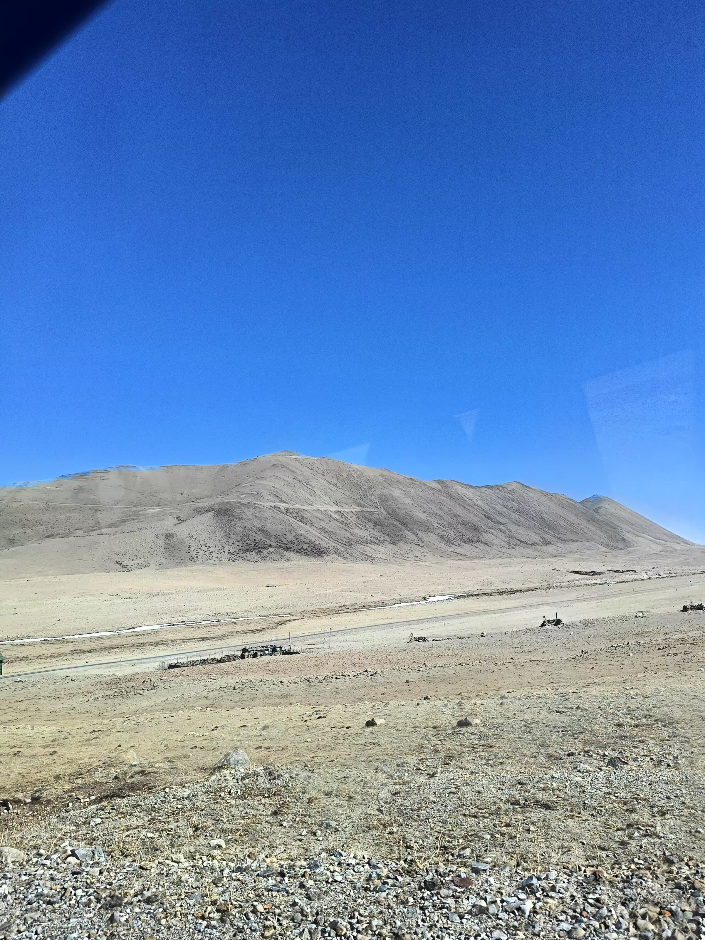 A high-altitude road crossing a broad, rocky Sikkim landscape