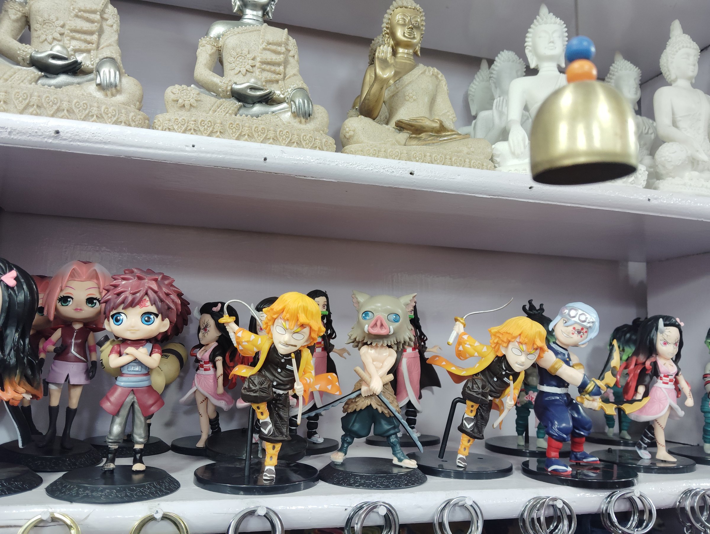 Colorful anime figures and Buddha statues displayed in a Gangtok shop