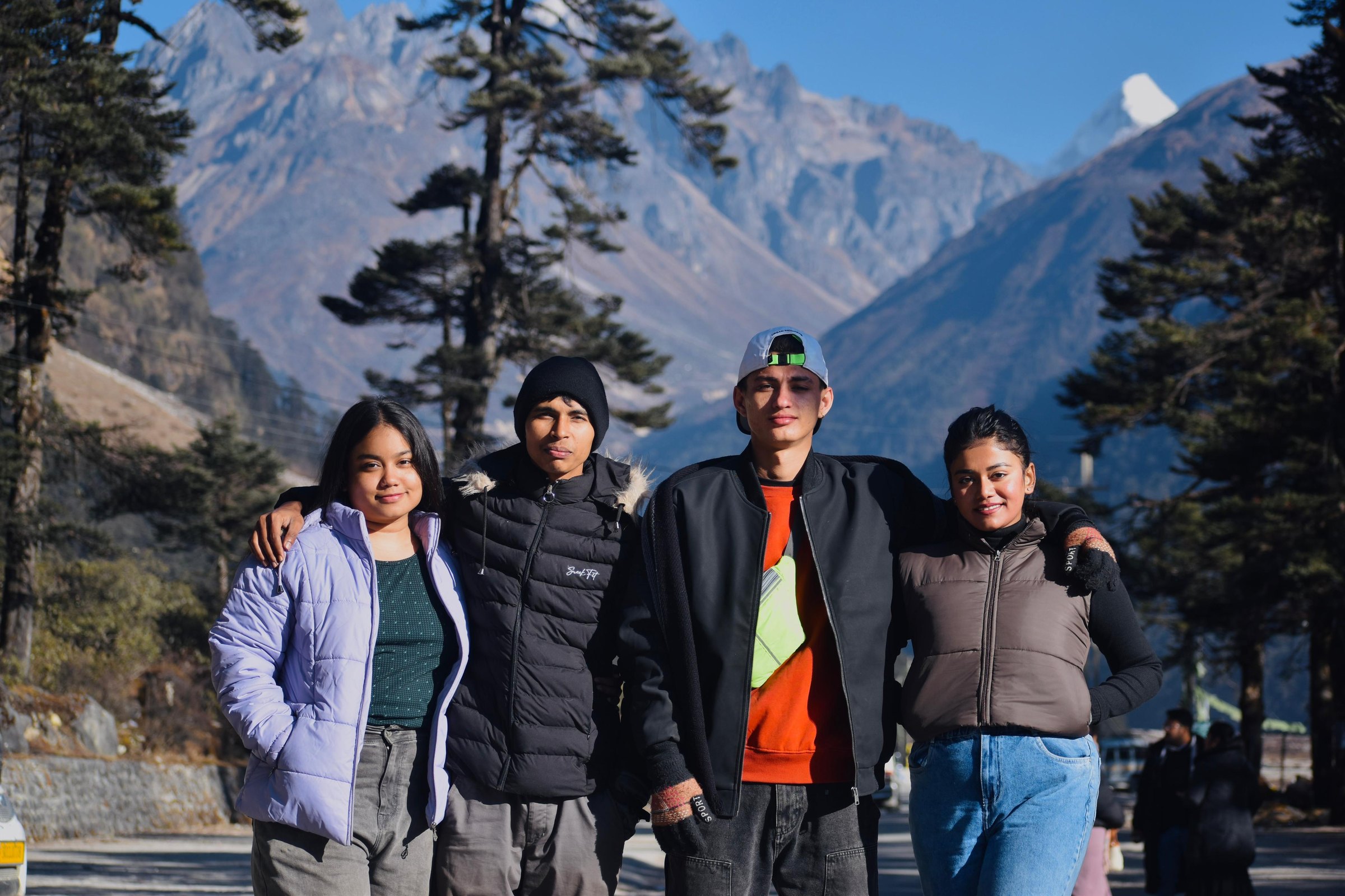 Four friends posing together against a dramatic mountain backdrop