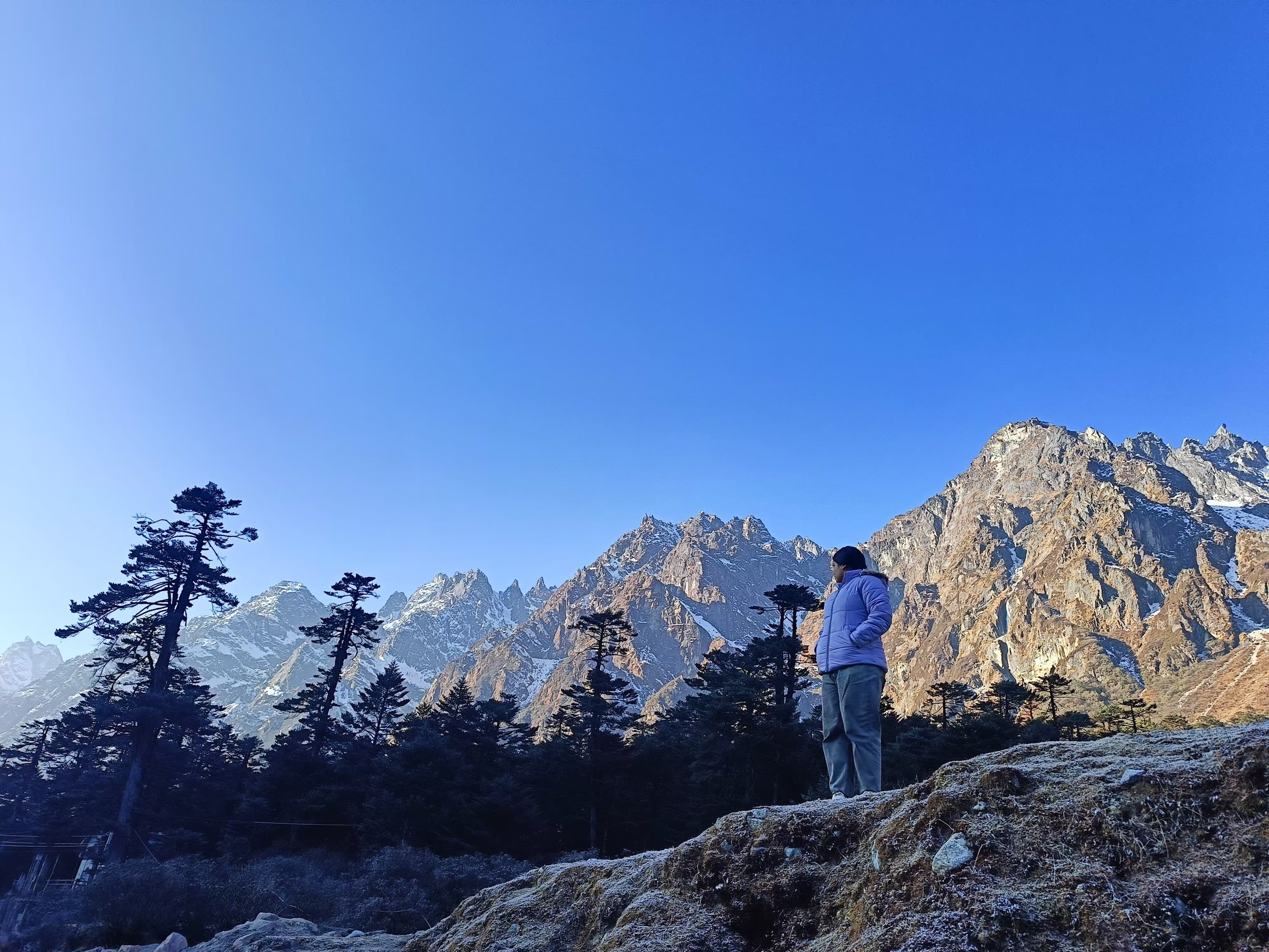 A traveler standing before dramatic sunlit peaks in North Sikkim