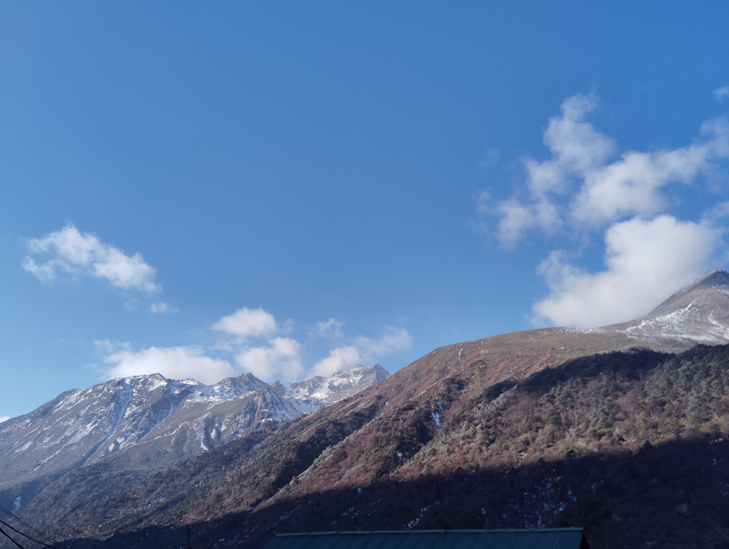 Snow-dusted Sikkim mountain ridges beneath a clear blue sky
