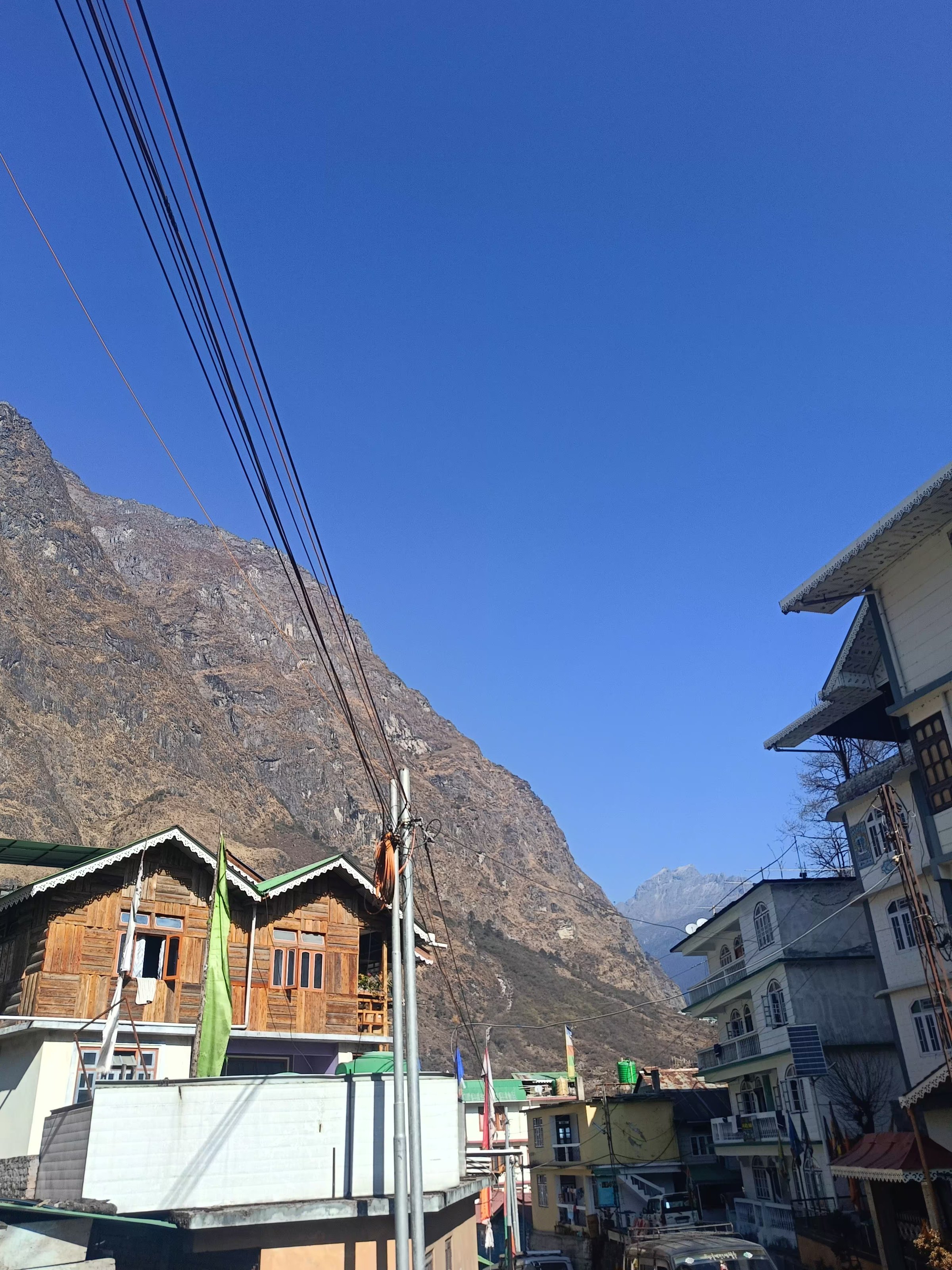 Traditional buildings set below steep mountains under a blue sky